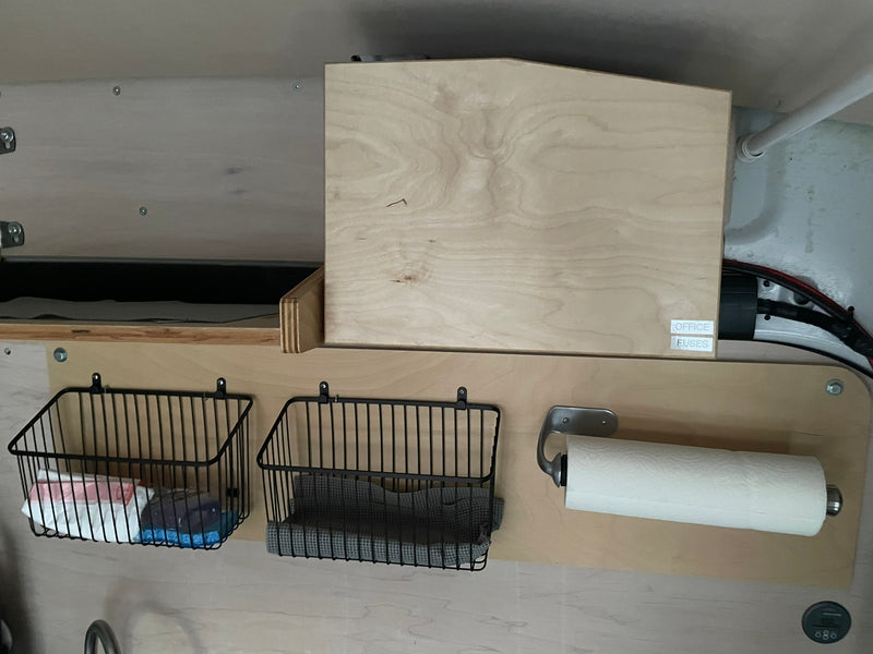 RV rental utility area: wood paneling, hanging storage baskets, paper towel holder, and labeled "OFFICE FUSES" box. — photo 8