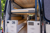 Modern rv rental camper van interior featuring comfortable bunk beds, tan cushions, and a control panel.