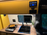 Sleek camper van kitchen with induction cooktop, sink, and power monitor. Ideal for rv rental journeys.