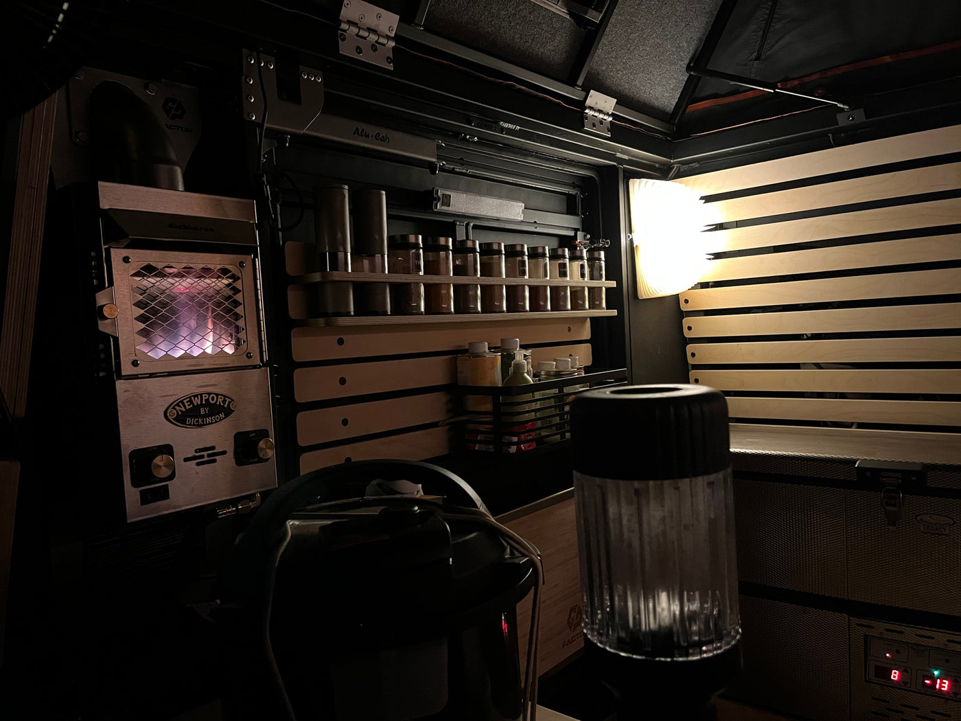 View of an RV rental interior at night, showing a glowing Dickinson heater, organized spice rack, and Alu-Cab storage. — photo 7