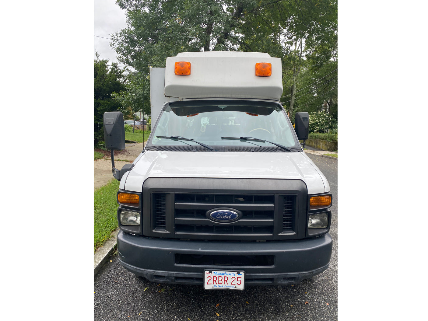 Front view of a white Ford box van, typical for commercial use or an RV rental. Massachusetts plate 2RBR 25 visible.