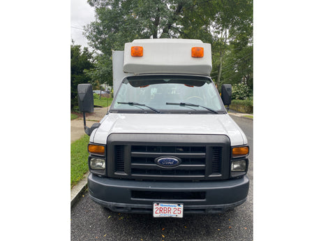 Front view of a white Ford box van, typical for commercial use or an RV rental. Massachusetts plate 2RBR 25 visible.