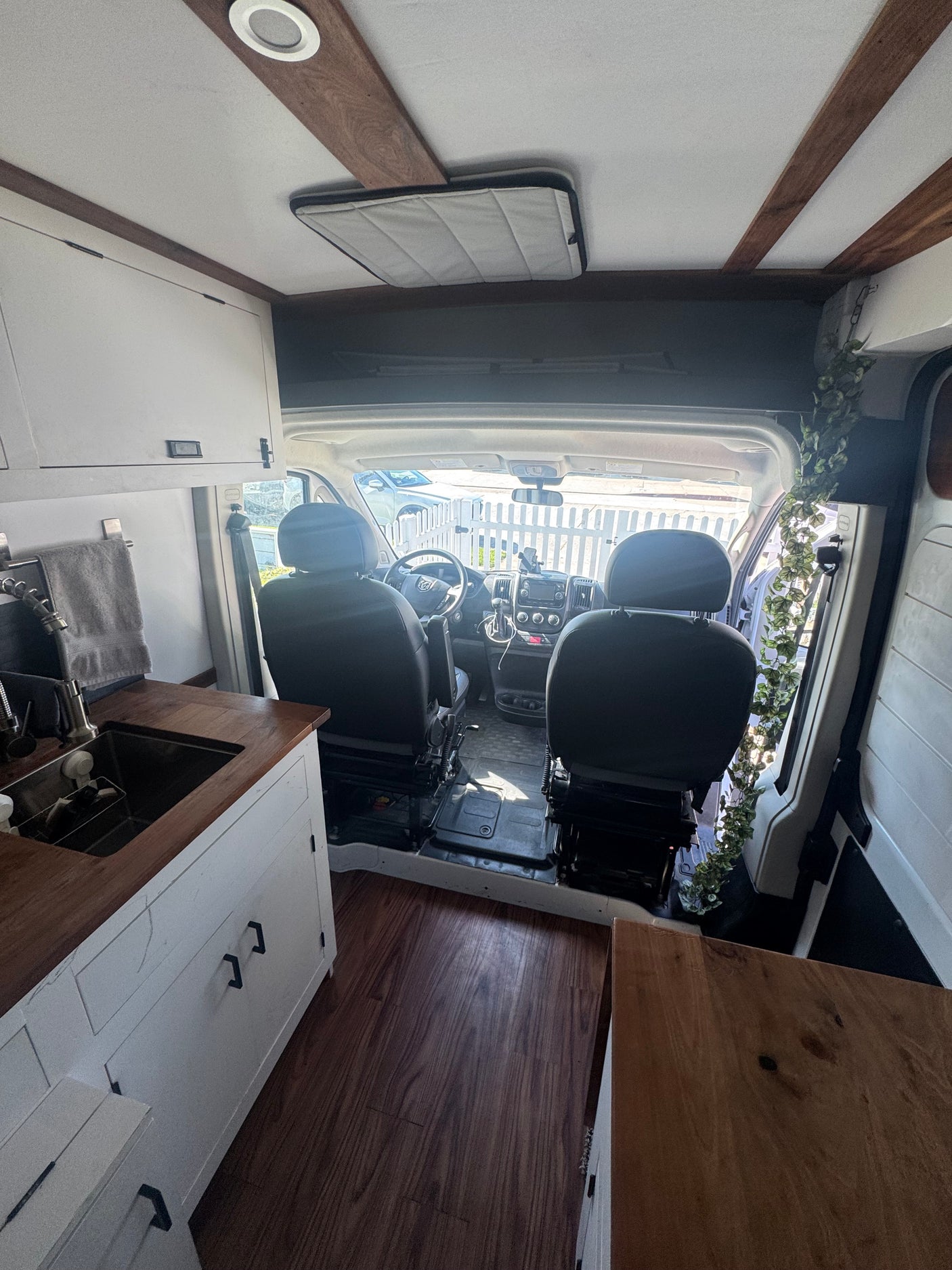 Cozy camper van RV rental interior. Includes custom kitchen, wood counters, recessed lighting, and driver's area.