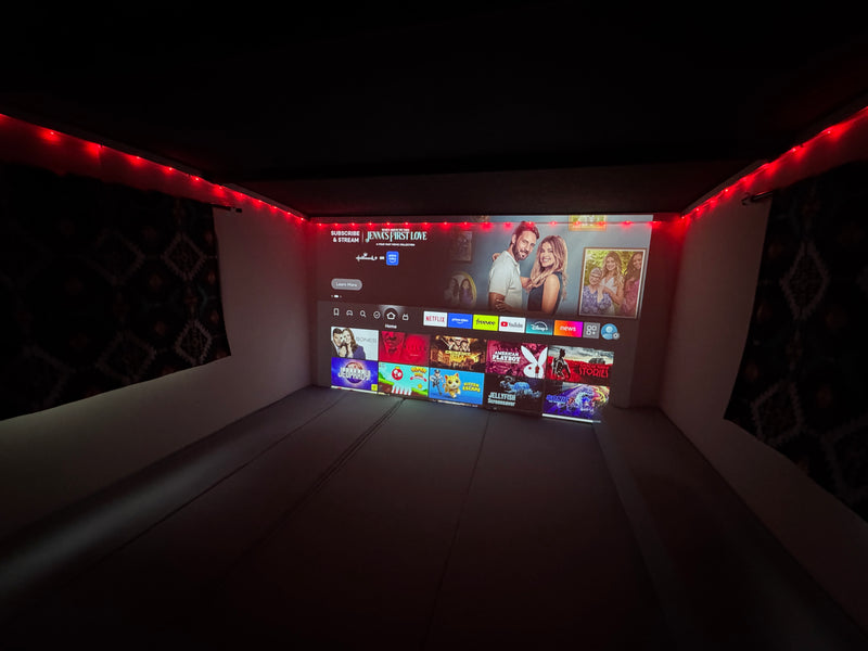 Cozy rv rental: a large projected screen displays streaming apps & movies under warm red string lights for entertainment. — photo 10