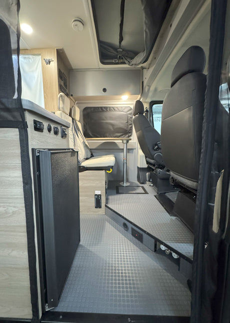 This RV rental offers a well-appointed interior: dinette, fridge, controls, and swiveling front seats for mobile living.