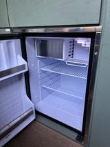 Bright interior of an open Isotherm compact refrigerator in an RV rental, showing wire shelves & freezer.