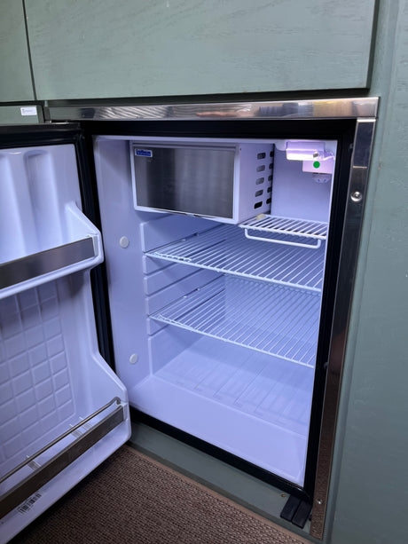 Bright interior of an open Isotherm compact refrigerator in an RV rental, showing wire shelves & freezer.