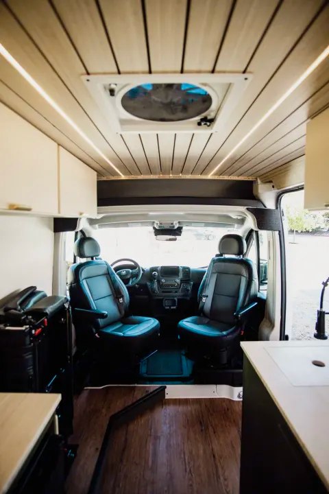  surrounded by rolling hills under a blue sky.|This RV rental campervan shows a comfy bed — photo 6