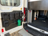 Efficient RV rental storage: Molle panel with pouches on van door, ladder inside. Perfect for organizing gear.