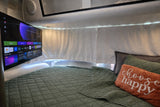 RV rental bedroom featuring a smart TV, comfy green bed with "choose happy" pillow, and warm LED lighting.