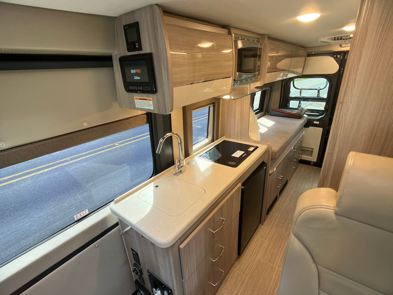 Inside a well-equipped RV rental: kitchenette with sink/cooktop, microwave, and smart controls, perfect for adventures. — photo 4