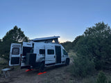 Scenic RV rental: White Winnebago Solis camper van parked with pop-top raised for a peaceful outdoor camping trip.