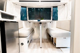 This inviting RV rental interior features a bright dinette with facing benches, a table, and windows looking out to nature.