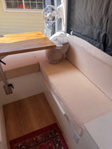 **Cozy RV rental interior** features a wooden dining table, plush bench seating, and a mounted fan.