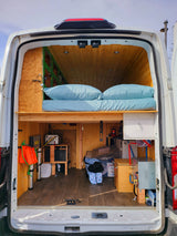 RV rental interior: A custom camper van setup with a raised bed, under-bed storage, and utility systems.