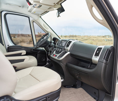 Step into this comfy rv rental. View of cream seats, driver's dashboard, and the open road ahead through the windshield.