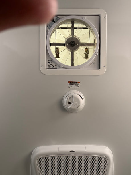 RV rental overhead: vent fan with controls, smoke alarm (with safety warning), and air return grill for comfort & safety.