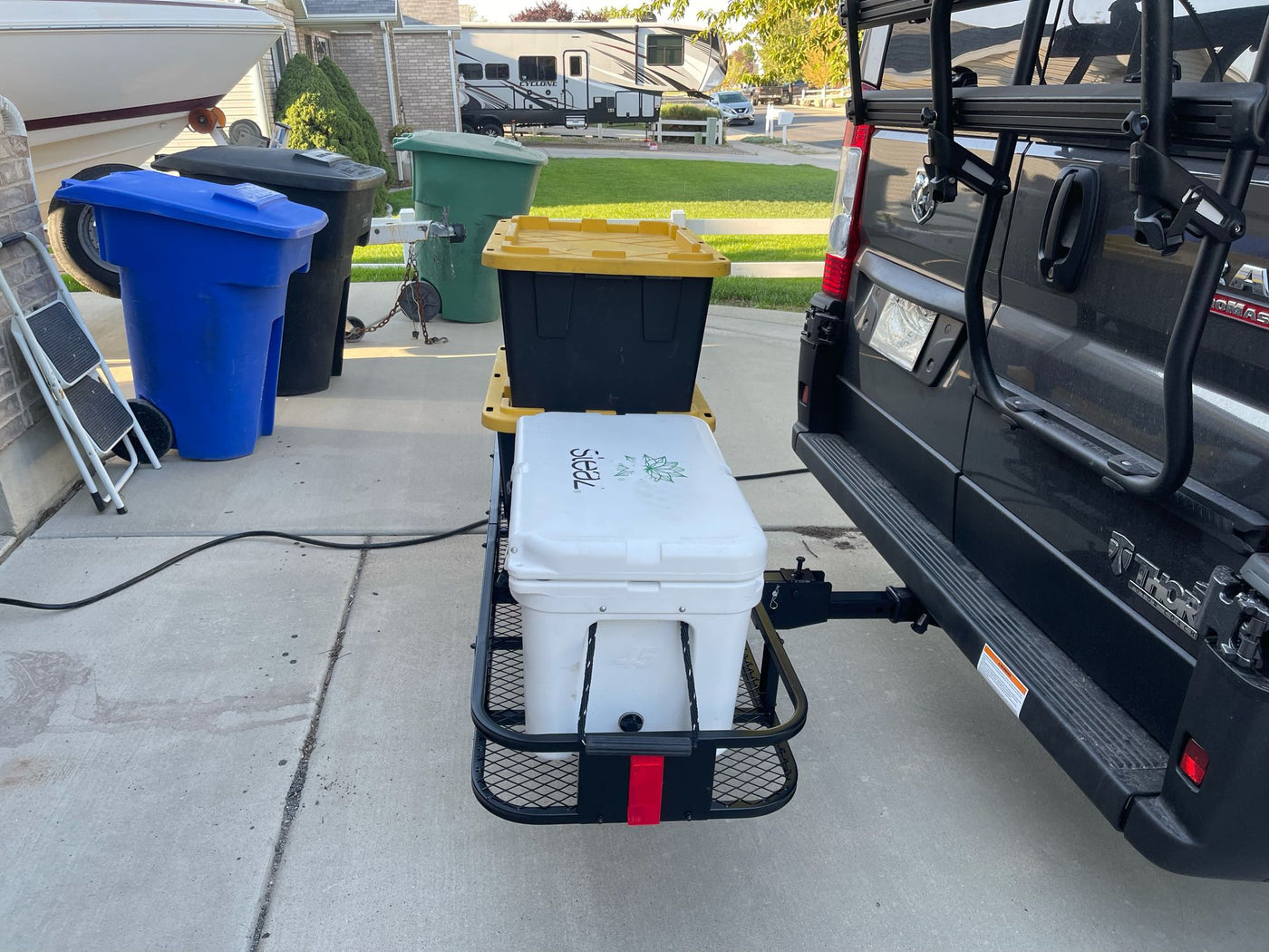 RV rental with rear cargo carrier, cooler, storage bin, and bike rack on a black van parked on a driveway. — photo 20