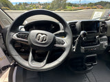 Ram van interior showing the steering wheel, dashboard, and a view of the road ahead, suggesting an RV rental.