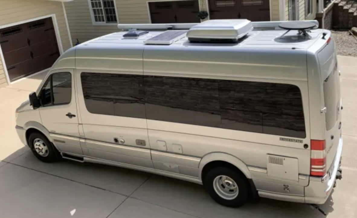 Silver Airstream Interstate RV rental, a luxury camper van with rooftop solar panels and AC units.