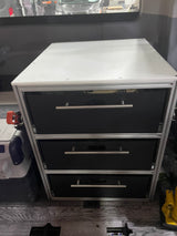 Compact custom drawer storage unit with three black drawers and silver handles, ideal for an RV rental interior.
