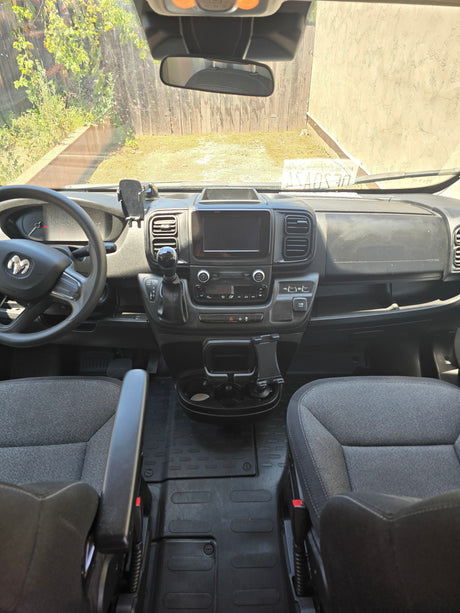 Interior of an RV rental van's front cabin, showing the dashboard, Ram steering wheel, seats, and backyard view.