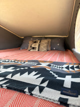 Comfortable RV rental bed with Pendleton blanket & pillows in a pop-top camper.