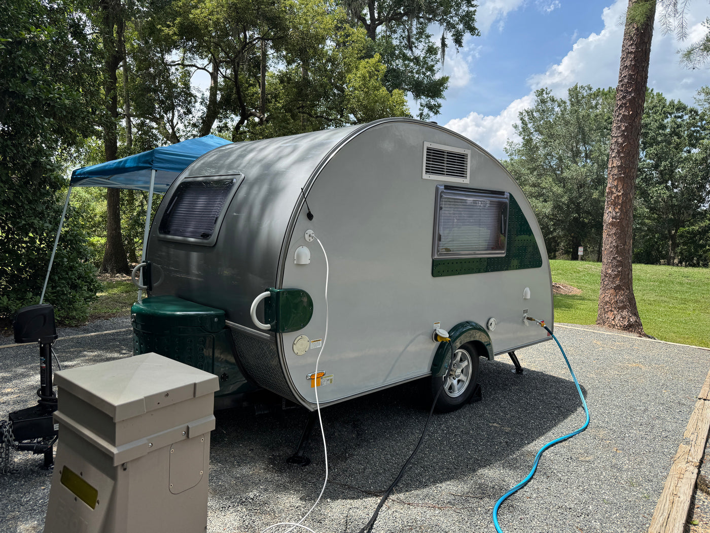 Teardrop RV rental set up at a shady campsite with utility hookups. Perfect for an outdoor adventure! — photo 2