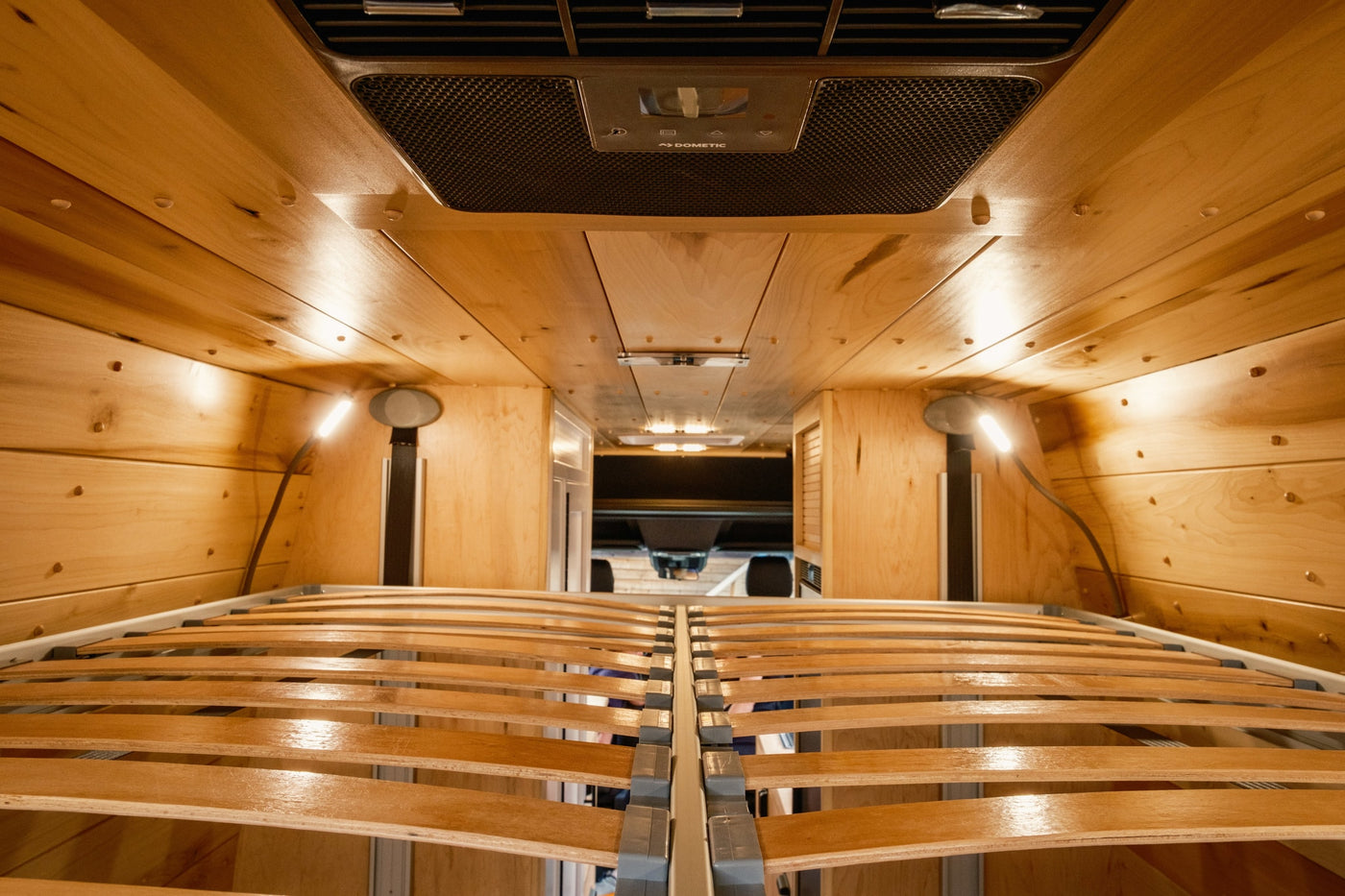 Cozy wooden interior of an RV rental, featuring a slatted bed frame and Dometic AC unit, perfect for travel. — photo 18