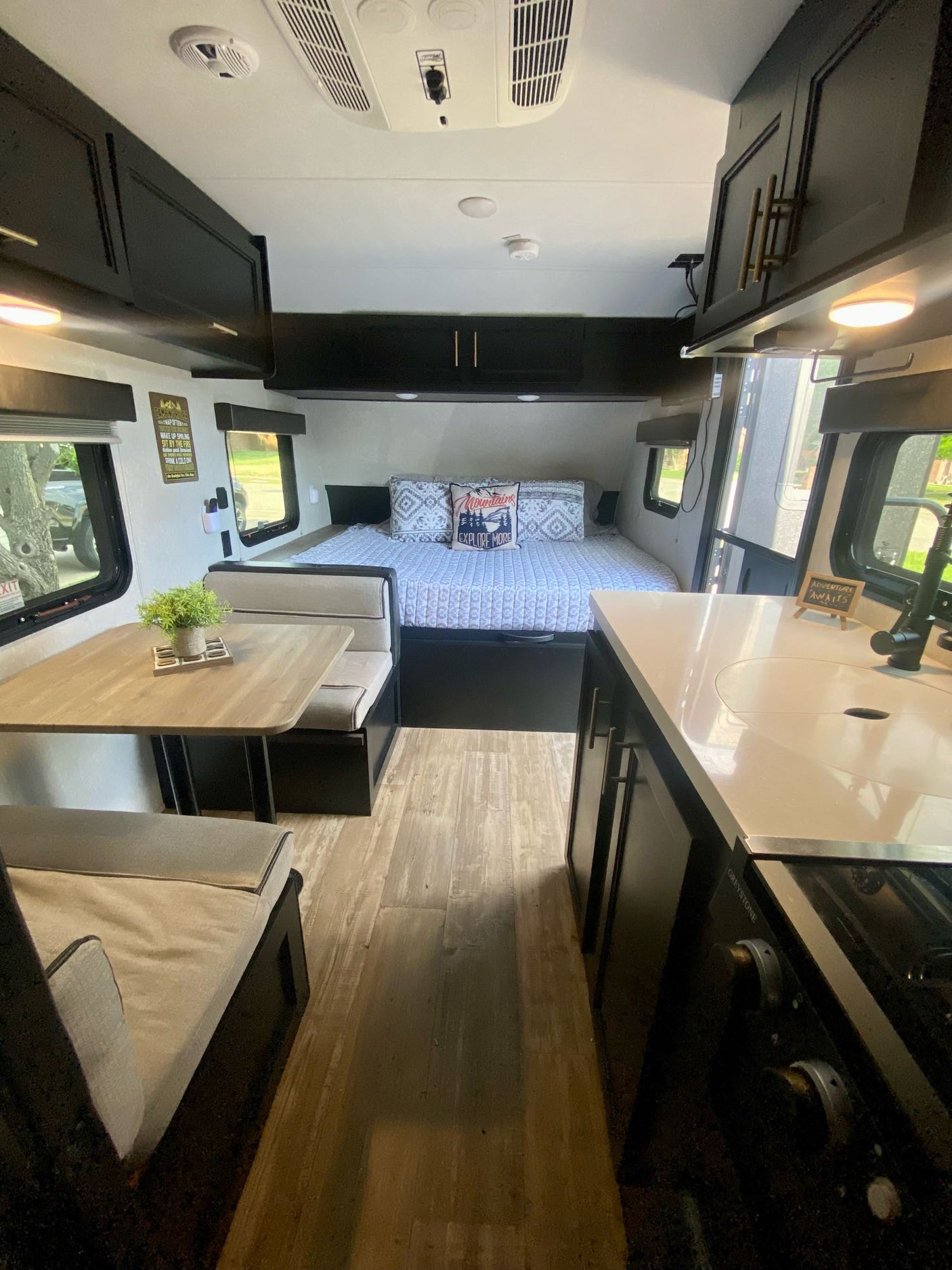 This RV rental interior showcases a compact layout with a cozy bed, a dining area, and a functional kitchen.