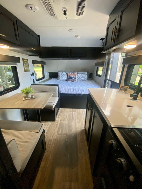 This RV rental interior showcases a compact layout with a cozy bed, a dining area, and a functional kitchen.