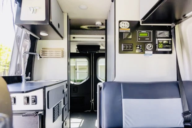  with a picnic table nearby for outdoor adventures.|RV rental interior: Modern camper van with front seats — photo 9