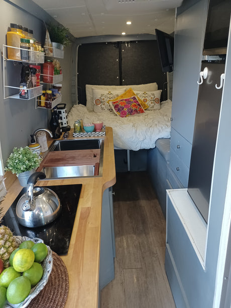 Cozy RV rental setup: a comfortable bed, compact kitchen with sink/stove, and smart storage.