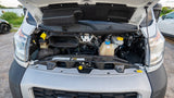 Open hood of a white RV rental van, revealing the engine bay with various fluid reservoirs, wiring, and headlights visible.