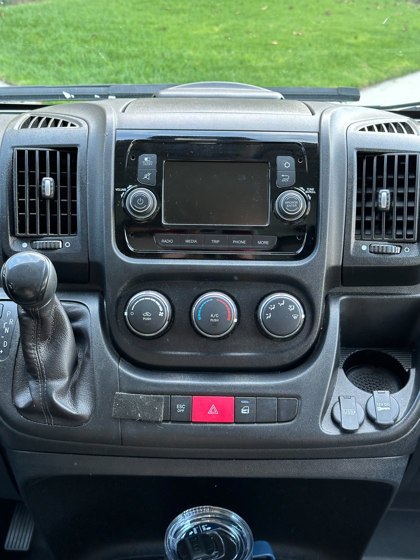 Dashboard of an RV rental: A detailed view of the center console with infotainment screen, climate dials, gear shifter, and power outlets.