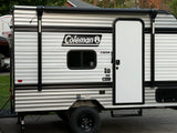 This Coleman RV rental, a striped travel trailer, features a side door, window, and retracted awning, ready for your next adventure.