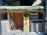 Inside an RV rental: Organized storage under the bed features a water tank, coiled hose, camping gear, and portable fridge.