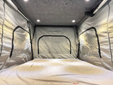 RV rental: Inside a cozy pop-top camper's sleeping area with a bed, fabric walls, ceiling lights, and ventilation.