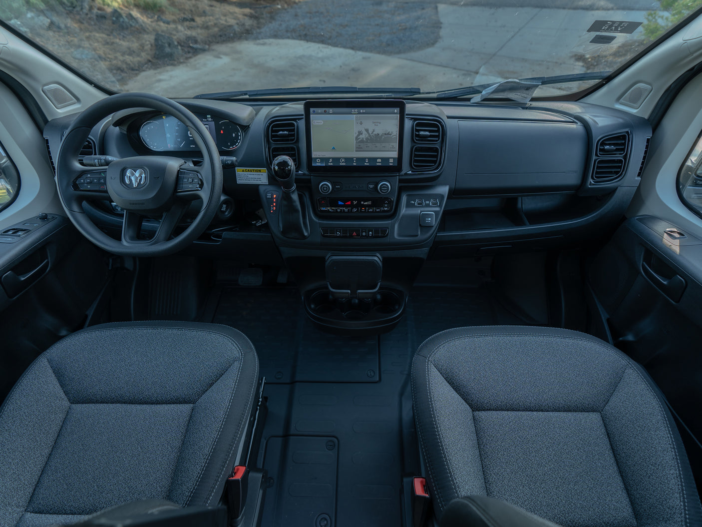 Interior view of an RV rental van's cockpit, featuring the modern dashboard, infotainment screen, and front seats.