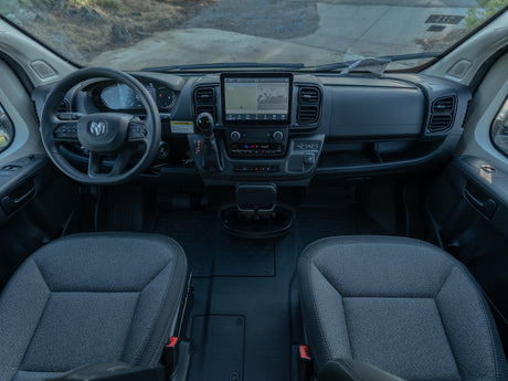 Interior view of an RV rental van's cockpit, featuring the modern dashboard, infotainment screen, and front seats.