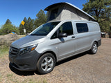 Silver Mercedes-Benz RV rental pop-top van parked on gravel, perfect for your next outdoor adventure.
