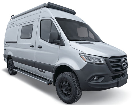 Silver Mercedes-Benz Sprinter camper van, ideal for RV rental. All-terrain tires, roof rack, running boards for adventure.