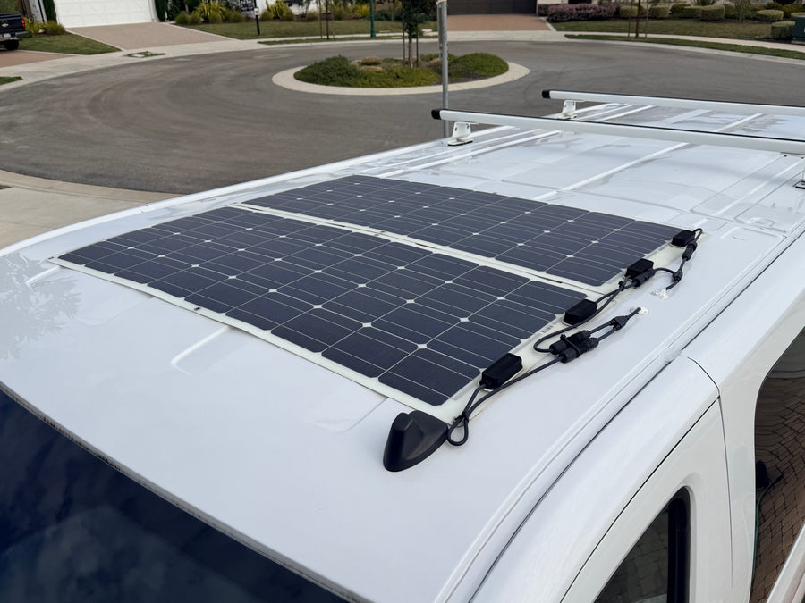 View of an RV rental roof with two flexible solar panels and wiring, providing off-grid power for adventures.