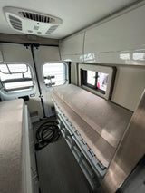 Clean RV rental interior: two sleeping areas (bunk beds on right), overhead storage, and ceiling AC for comfort.