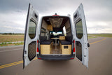 Step inside this RV rental's custom camper van interior featuring seating, a table, and lights for road trips.