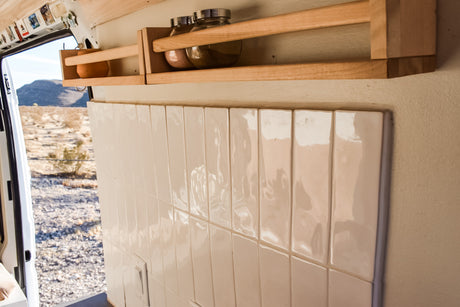 RV rental: Interior kitchen with tiled wall, wood spice shelves, and desert view from the open door.