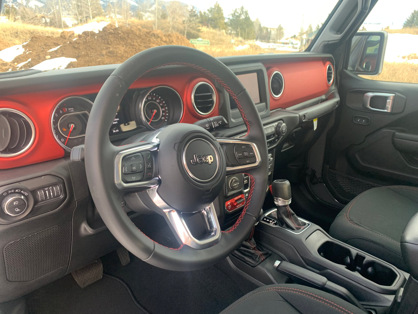 Inside a rugged Jeep with a red dashboard & advanced controls. Ideal vehicle for an outdoor RV rental journey.