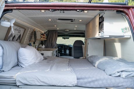 Cozy camper van interior, perfect for an RV rental adventure. Features a comfortable bed, mini-kitchen, and clever storage.