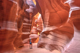 Woman stands amazed in a vibrant slot canyon, its swirling sandstone walls glowing from above. Start your RV rental journey here!