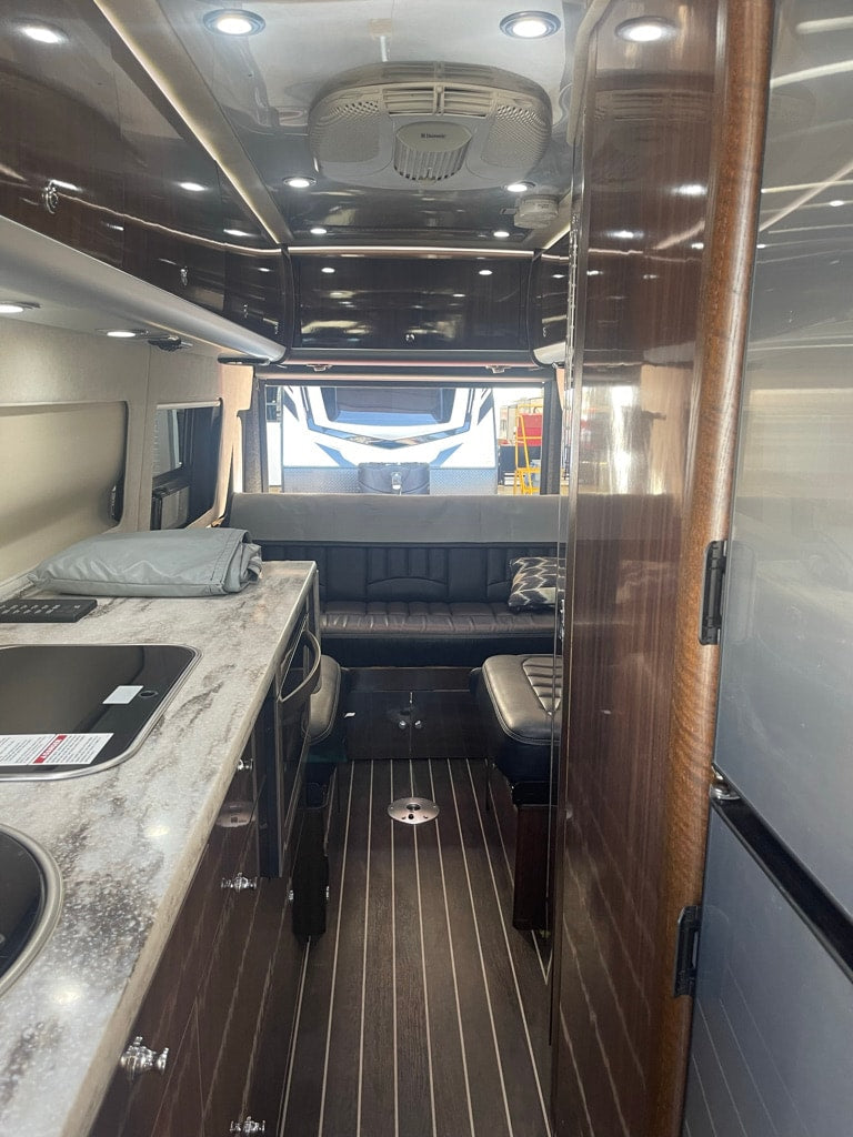  parked on a paved lot on a cloudy day.|Silver camper van RV rental with open doors — photo 3